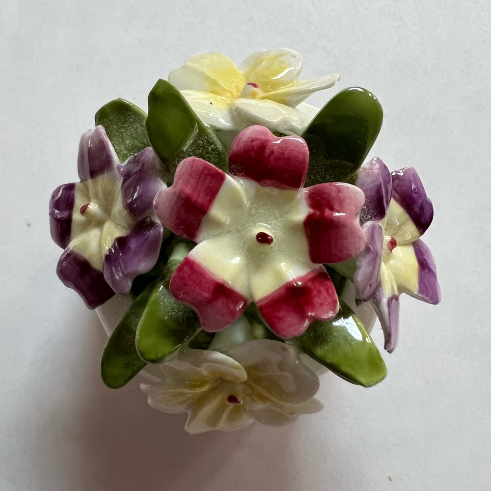 Miniature vintage basket of primroses. Five flowers purple, yellow and magenta.
